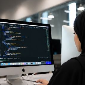 A girl writing a code on an iMac desktop