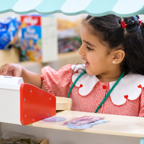 A nursery-age girl plays with a toy cash register
